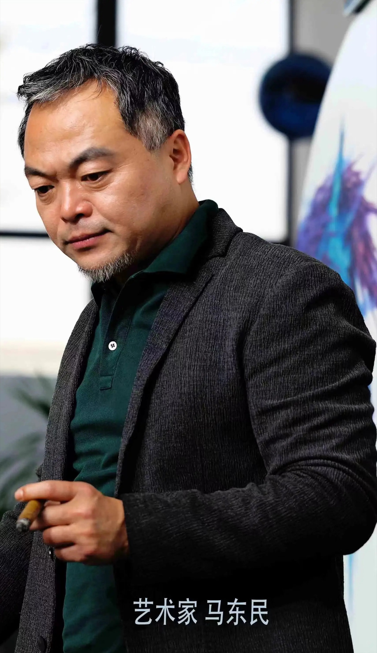 Portrait of artist Ma Dongmin in his studio beside a blue-horse painting